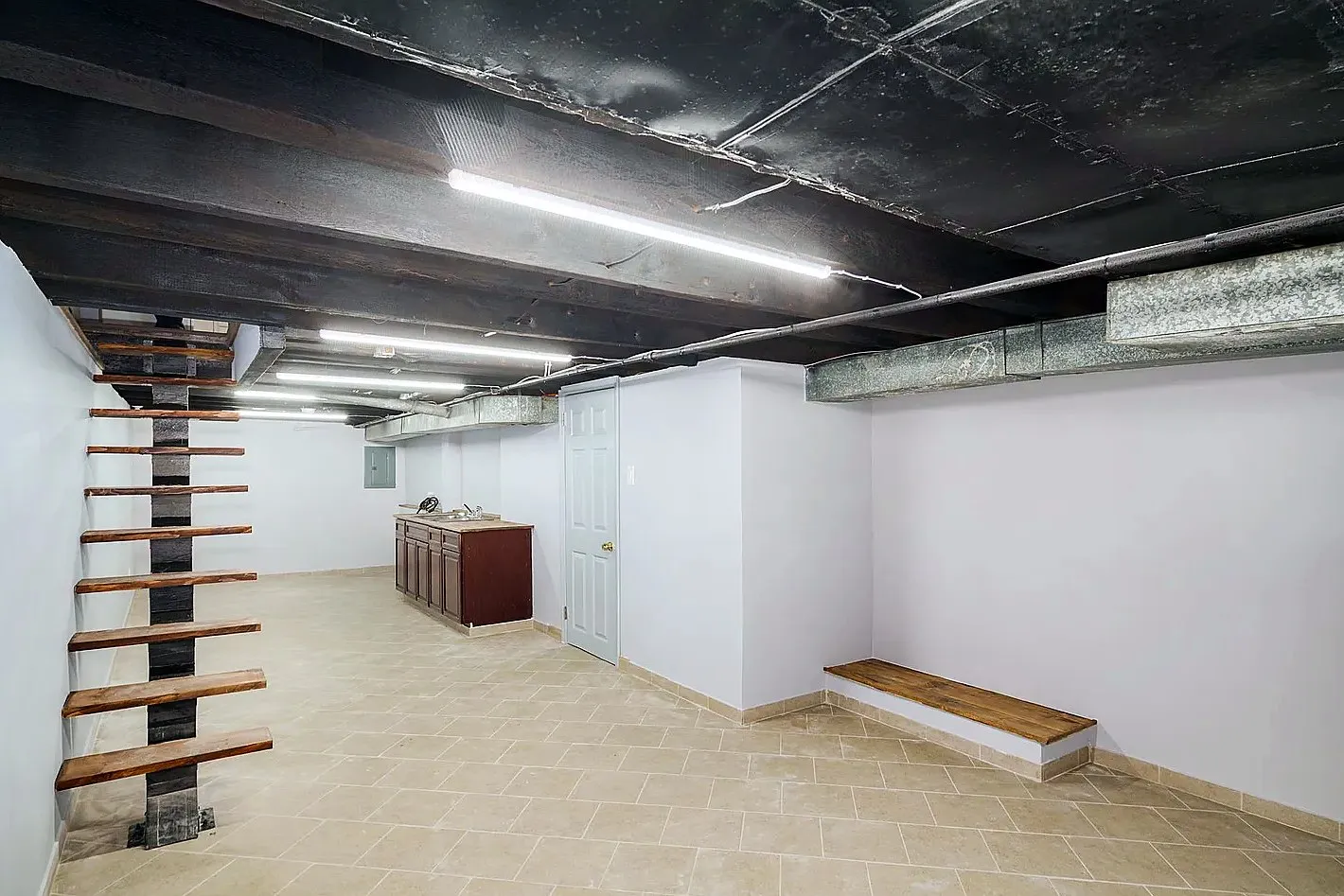 After: the basement, from a bare slab and stone walls to a tiled floor, an open stair and a kitchenette