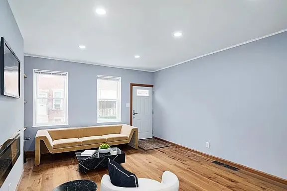After: the front room, from a crystal chandelier and dark laminate to recessed lights and wide-plank oak