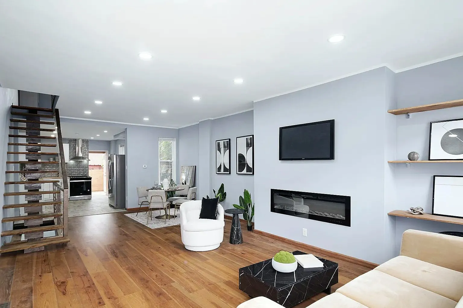 The same living room after, with smooth painted walls and an open stair