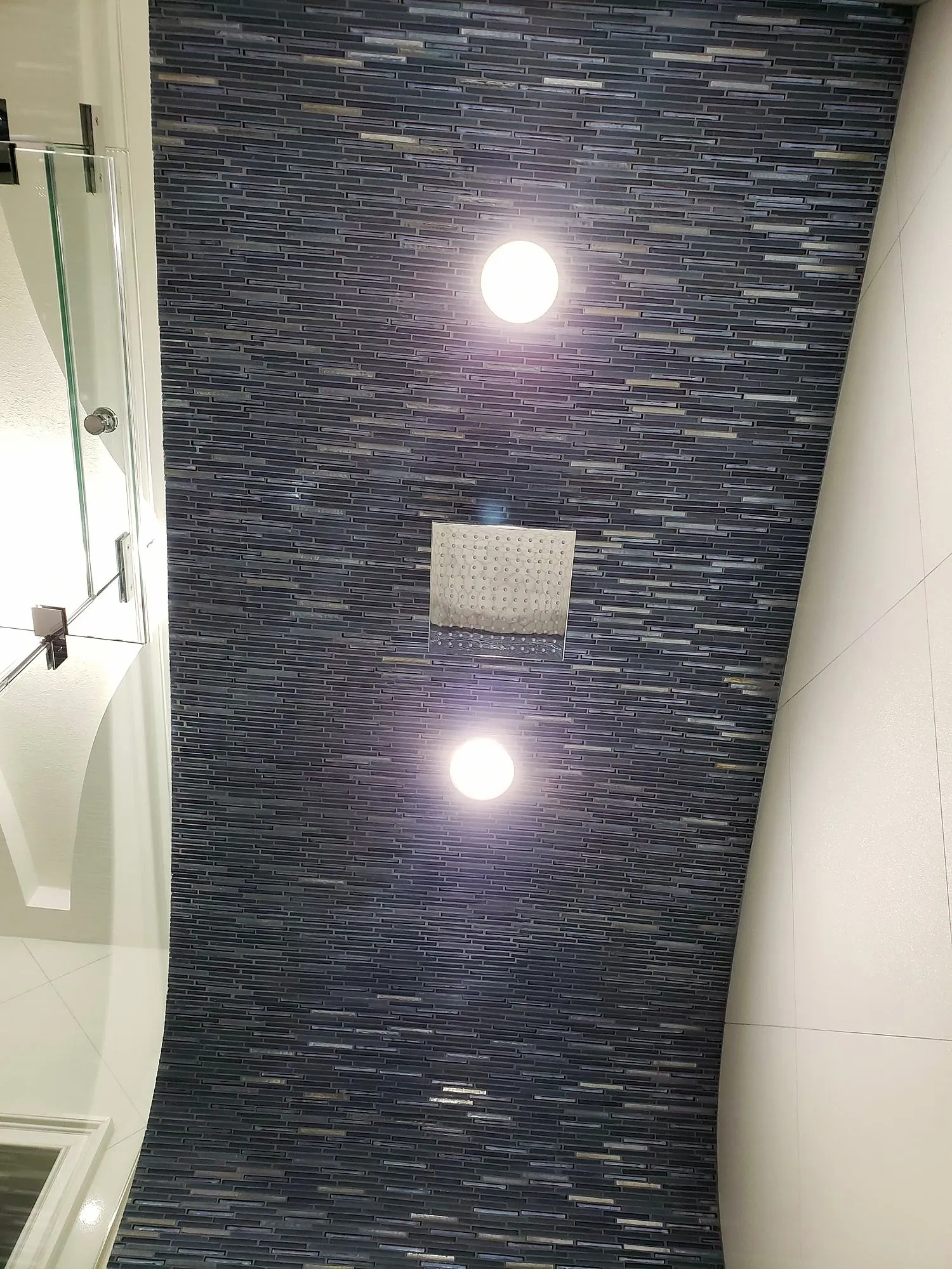 Blue mosaic shower wall with two recessed lights above