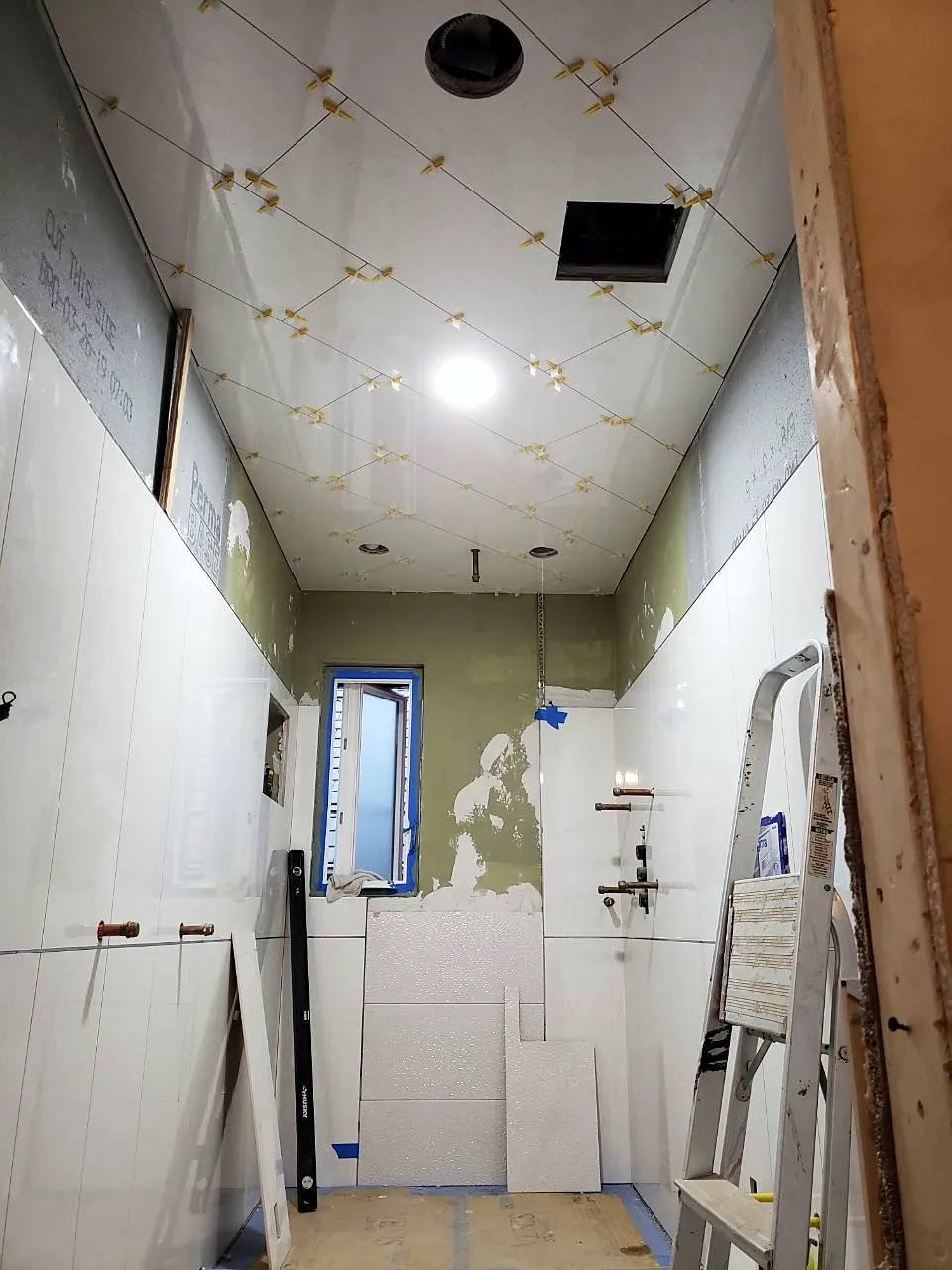 Ceiling and wall tile set with leveling clips in a narrow bathroom
