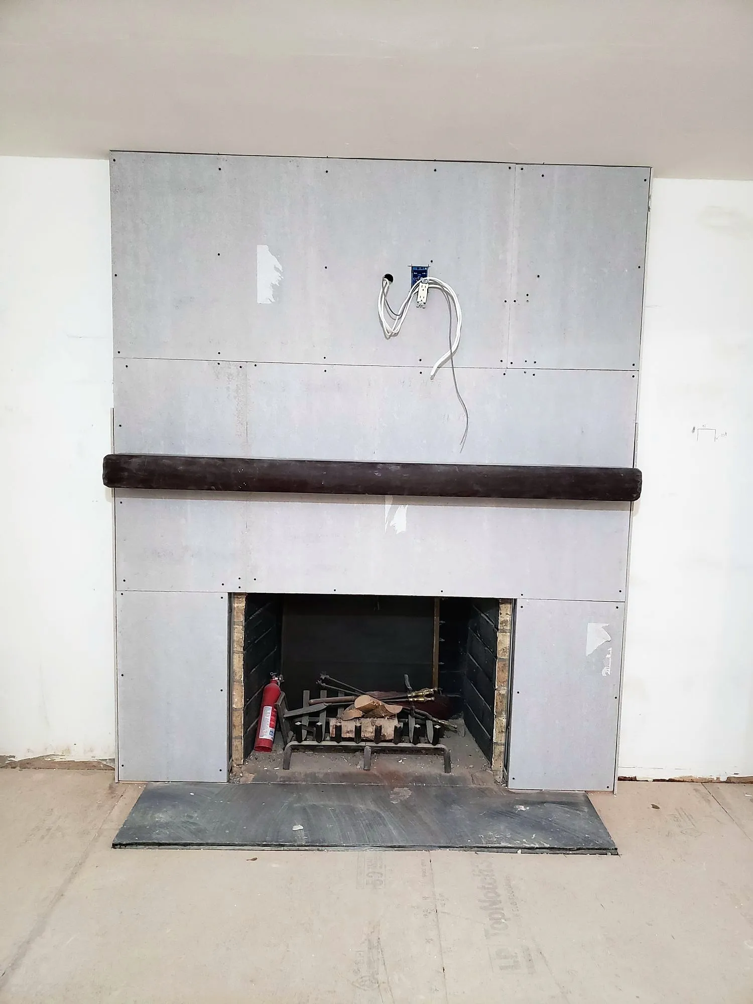 Fireplace chase covered in cement board with wiring roughed in before stone