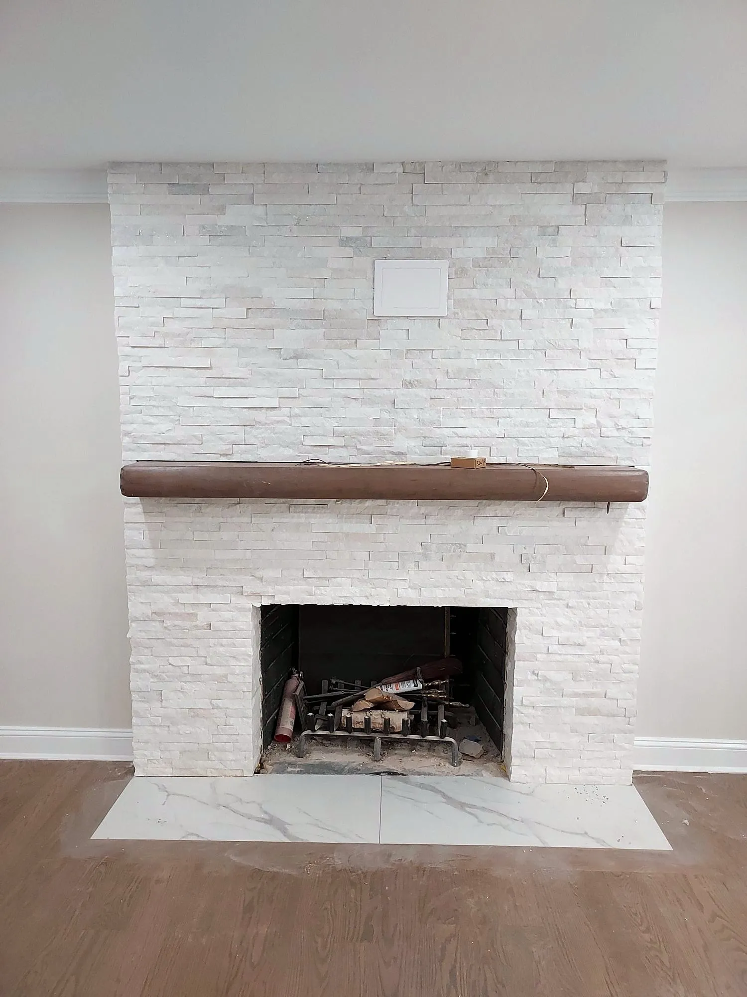Finished stacked-stone fireplace surround with wood mantel, straight on