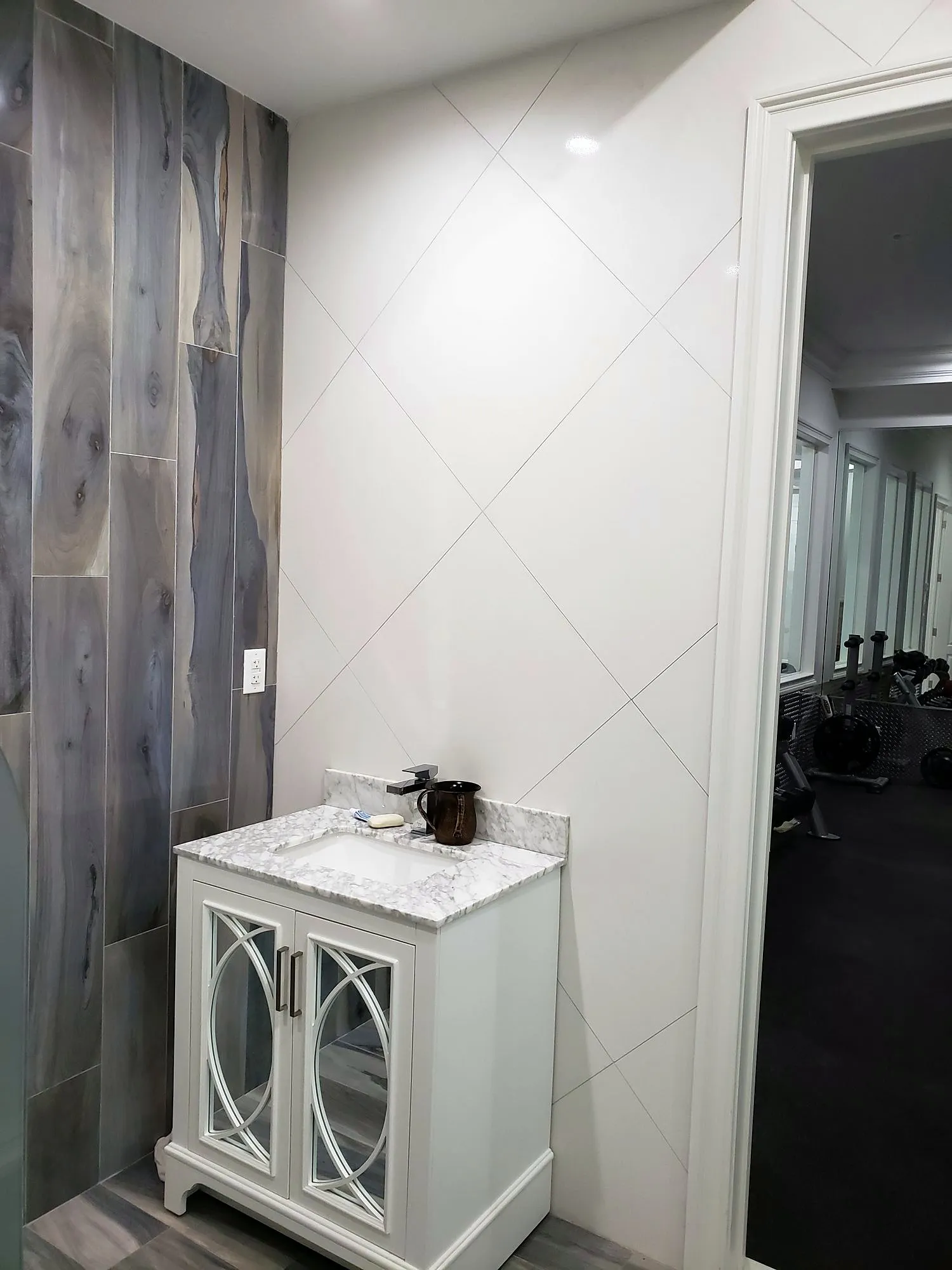 White furniture-style vanity with mirrored doors against wood-look tile