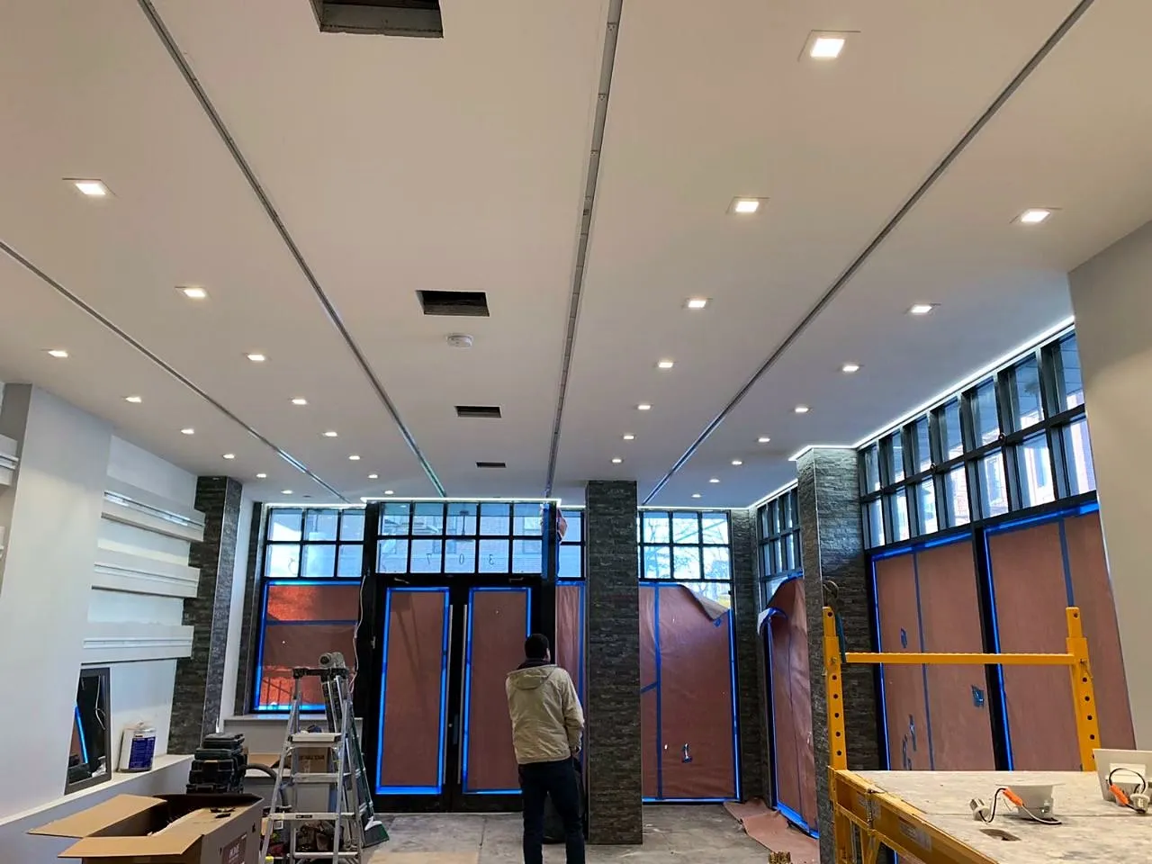 Commercial space with new ceiling, storefront glazing and lighting during finishing