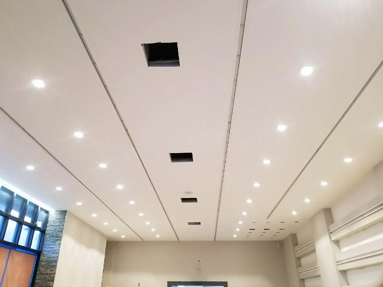 Freshly skim-coated and painted white ceiling with recessed lights in a renovated interior