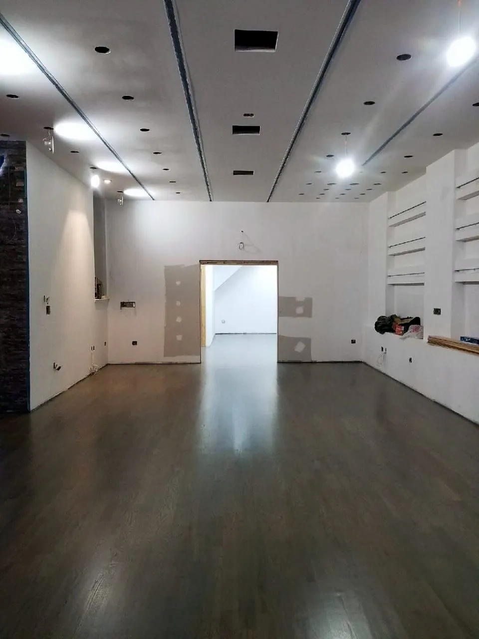Finished commercial interior with a dark hardwood floor, white walls and recessed lighting