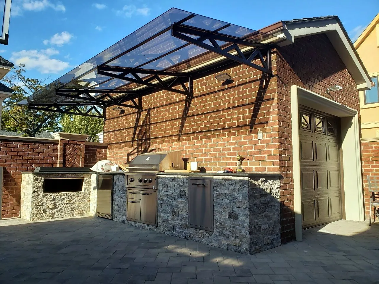 Outdoor kitchen with stone cladding and a built-in grill under the canopy