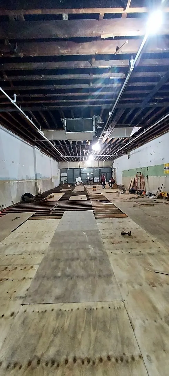 Exposed joists overhead with plywood subfloor strip and framing lumber
