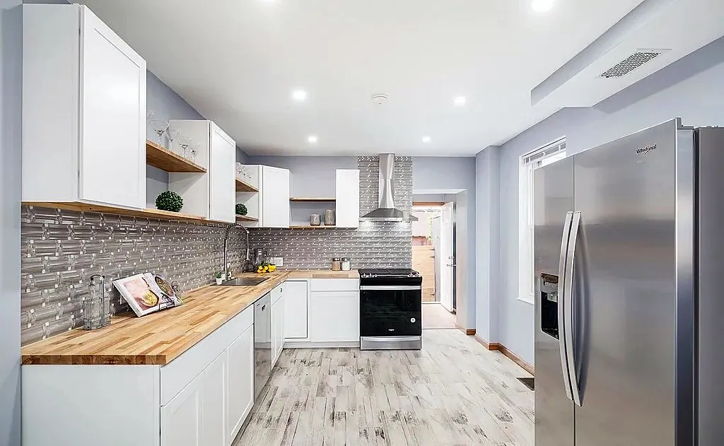 Renovated rowhouse kitchen seen from the dining side with a stainless refrigerator