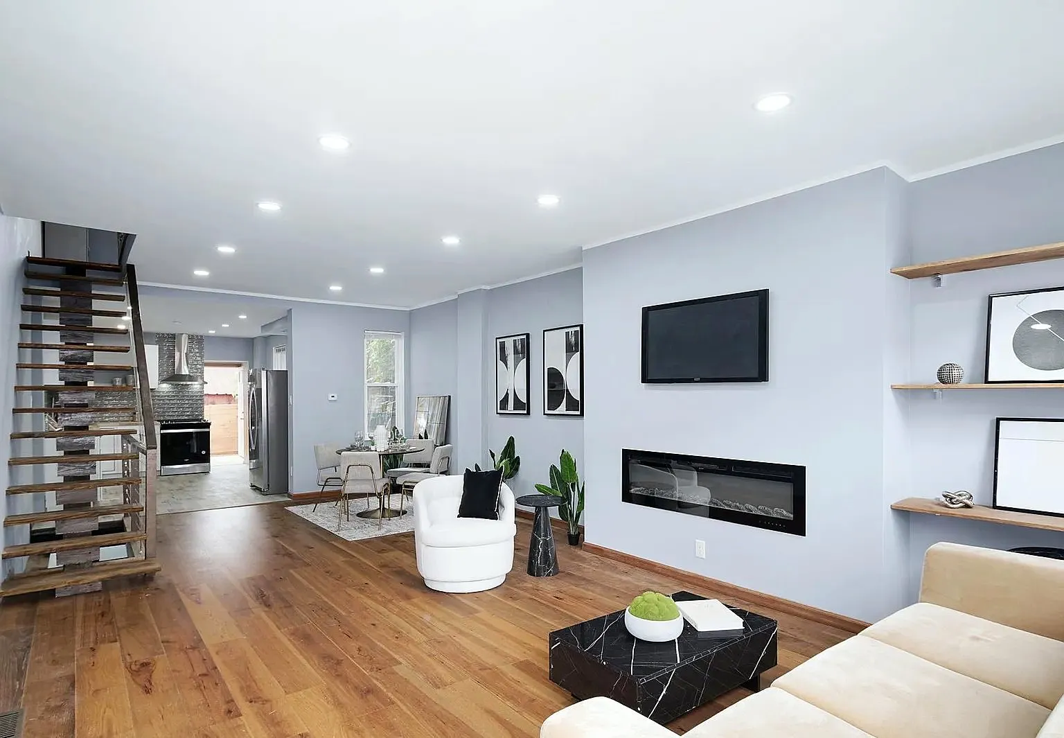 Renovated living room with a linear fireplace wall, floating shelves and wide-plank floors