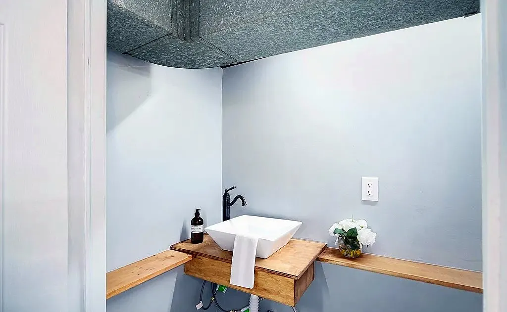 Bathroom with vessel sink on a wood floating vanity and black wall-mounted faucet