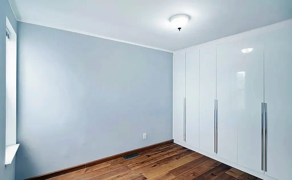Upstairs room with pale blue walls, white crown molding and full-height wardrobes