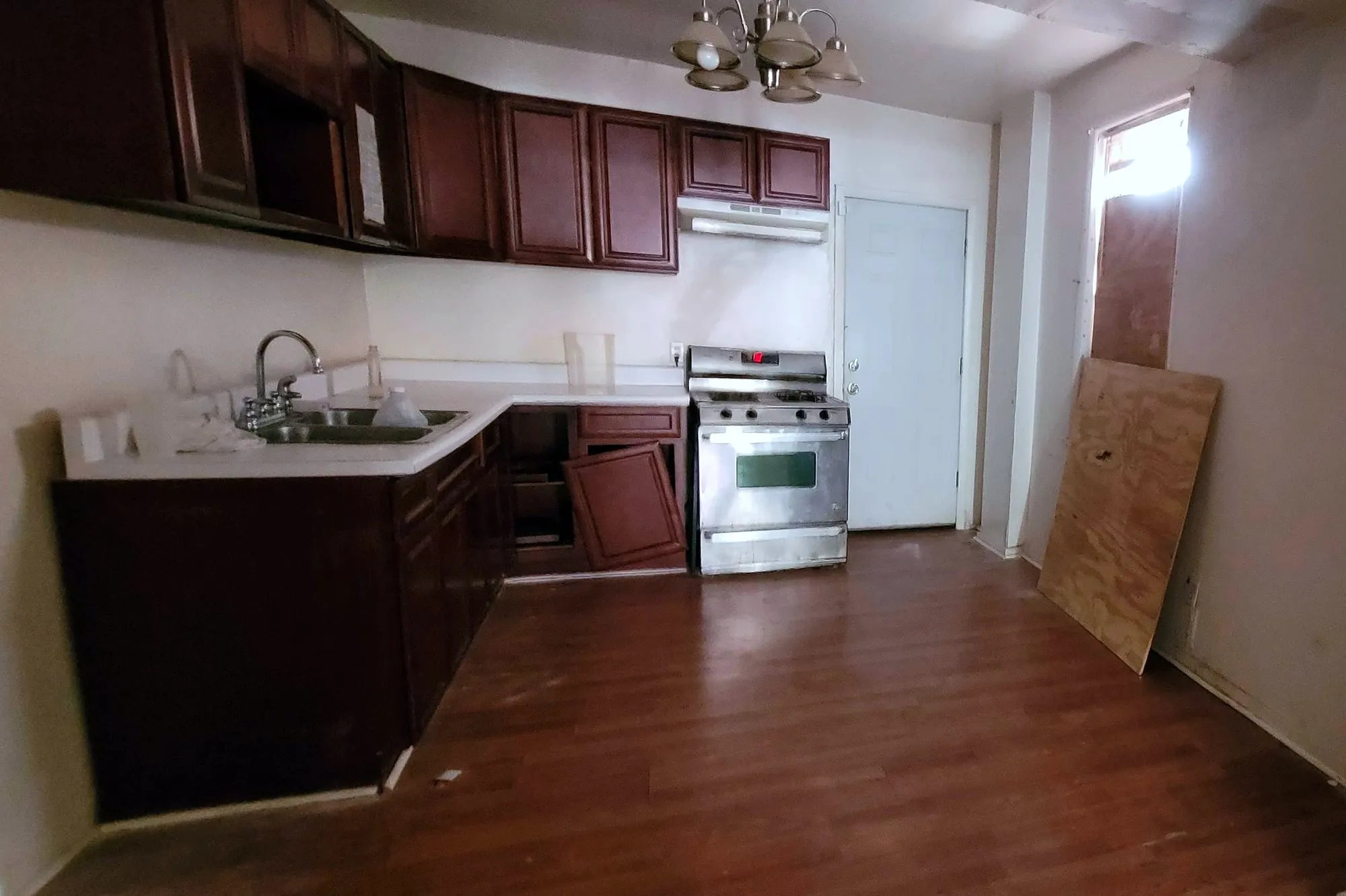 The old kitchen from the front of the room, with cherry cabinets, a sink run, the range and the back door
