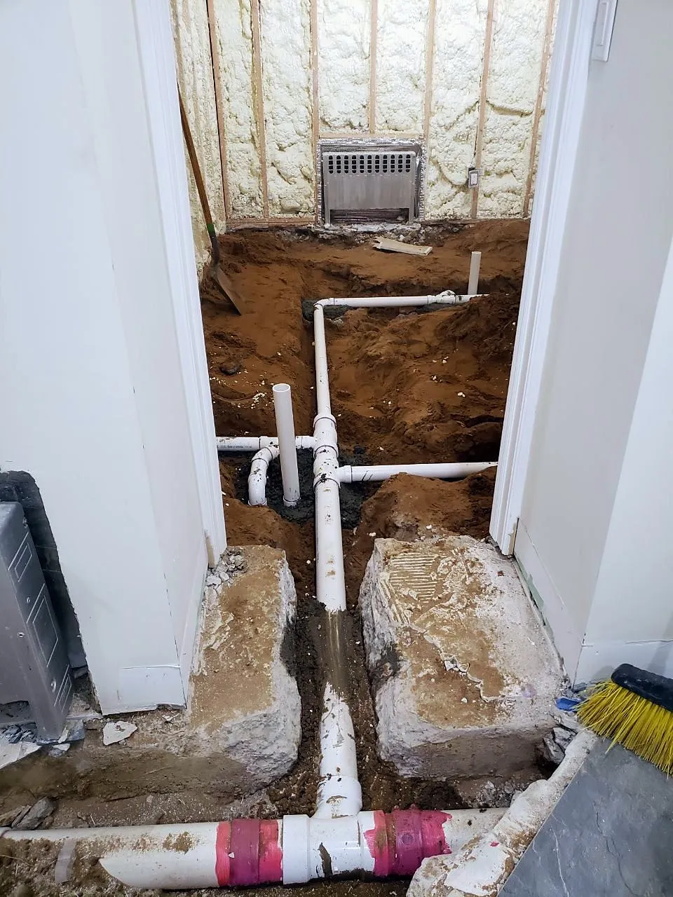 Trench cut into the basement slab with new PVC drain lines