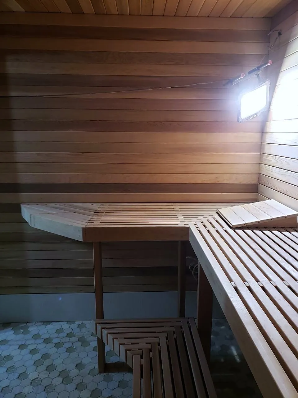 Finished cedar sauna interior with two-tier slatted benches and warm lighting